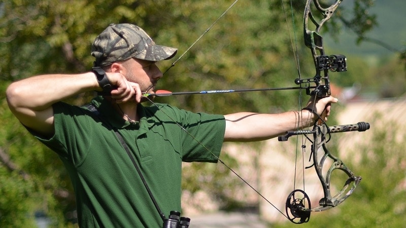 a man sighting in a bow