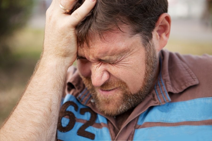 a man touching his head in agony 