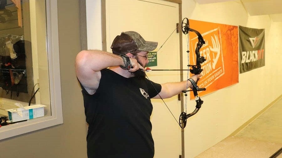 man shooting a bow indoors