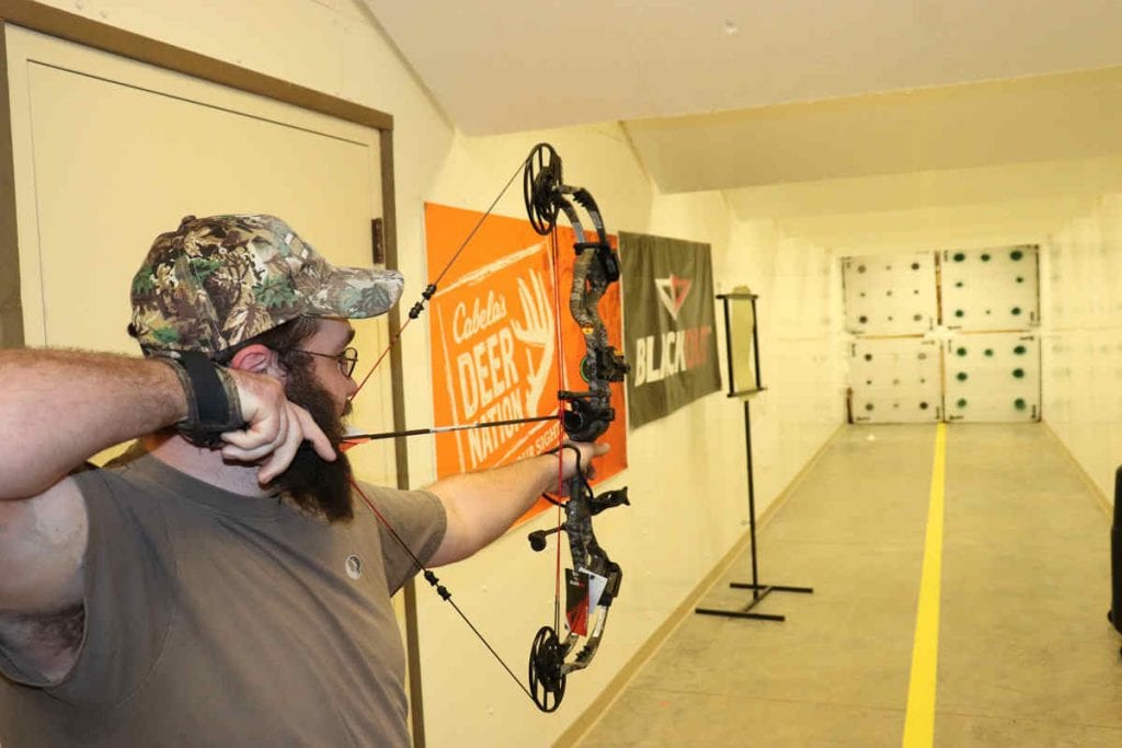 a man shooting a bow at a target indoors