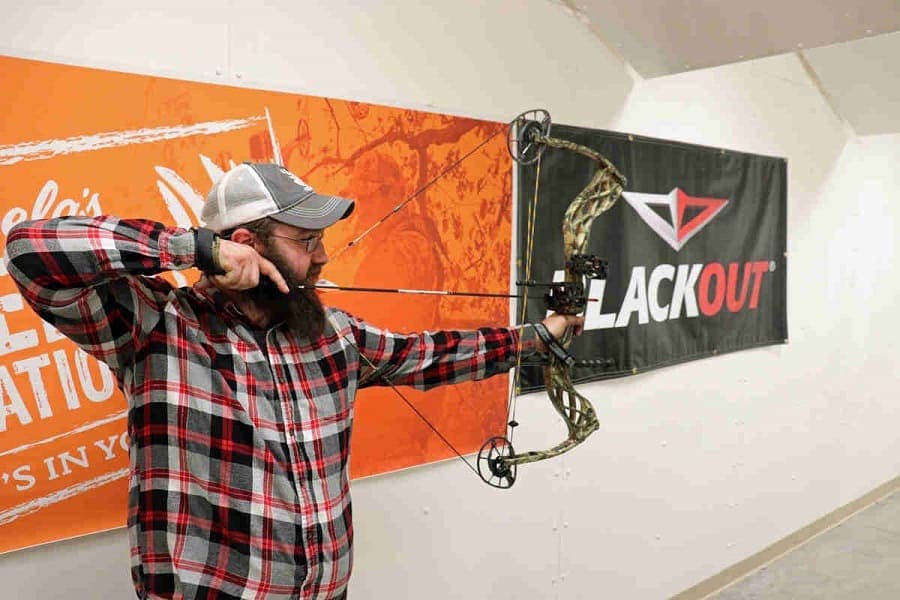 man shooting a compound bow