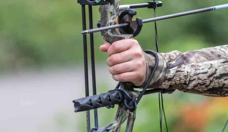 a hand holding a compound bow