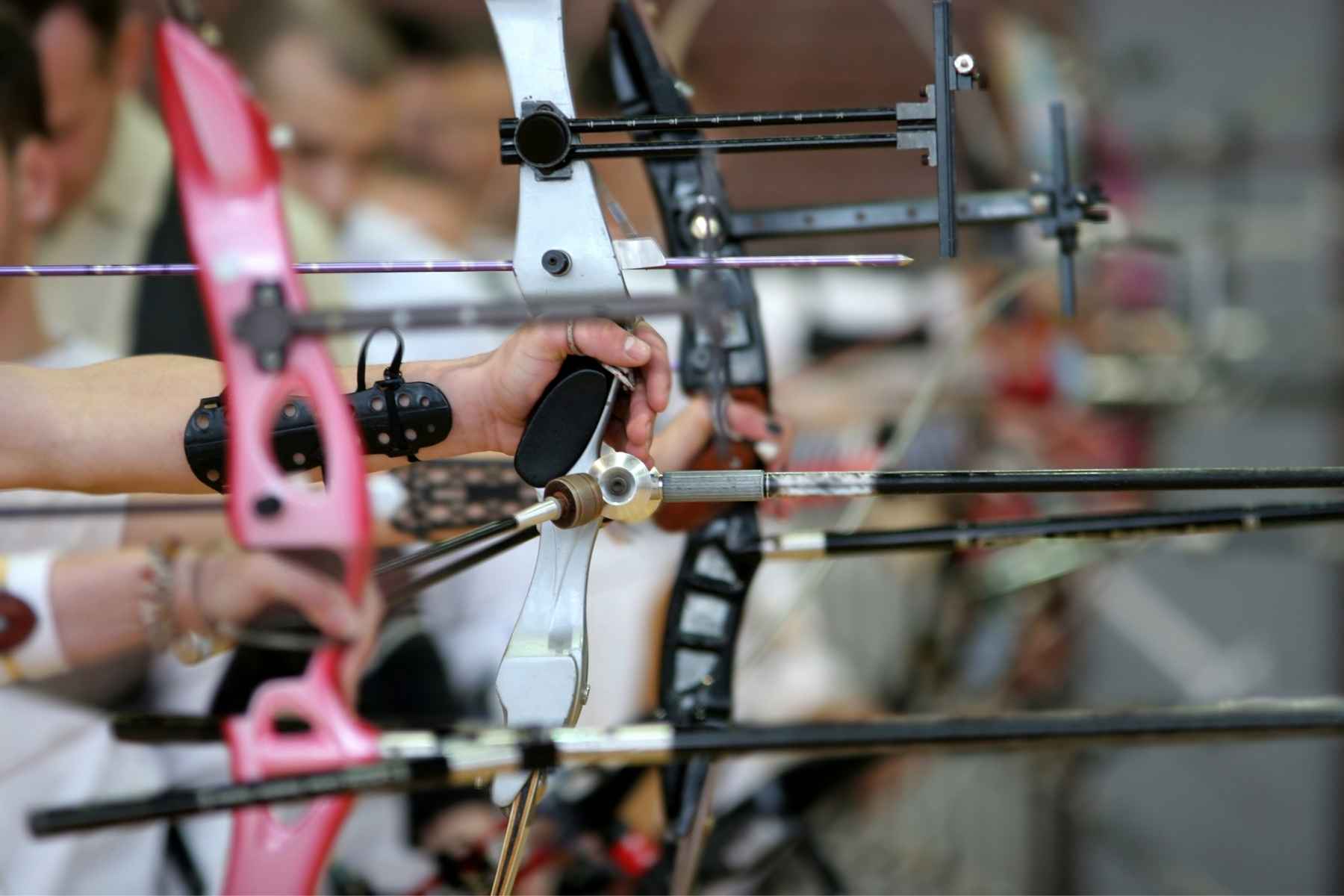 a bunch of recurve bows held by people aiming