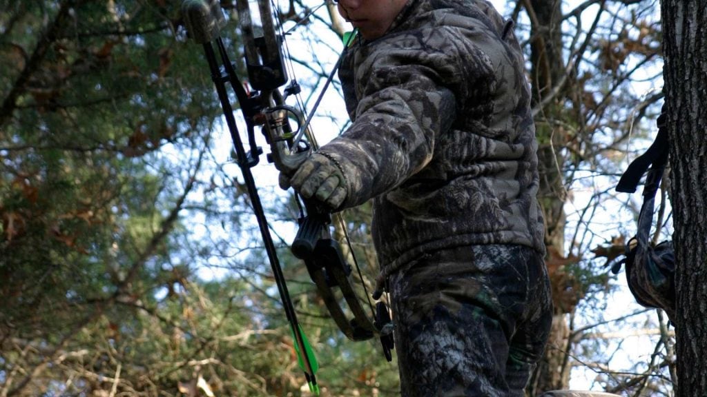 hunter in treestand aiming with bow