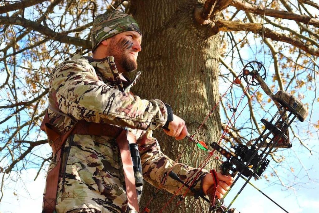 a hunter in his treestand with his compound bow